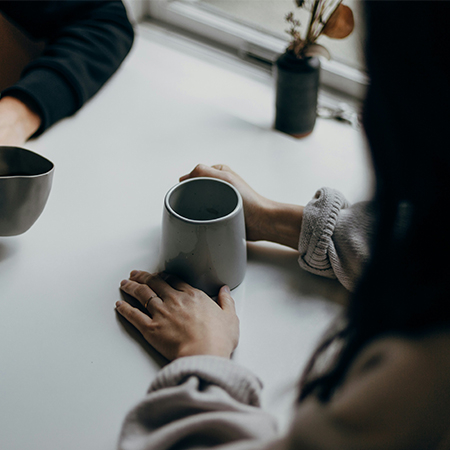 Two unidentifiable people sitting a table having coffee.